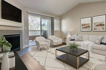 A living room with a fireplace and a white couch at The Village at Seeley Lake Apartments, Lakewood, WA